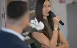 Kobieta w długich włosach z mikrofonem w reku rozmawia z mężczyznom odwróconym tyłem