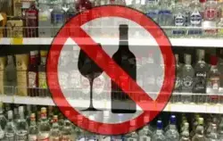 półki z alkoholem w tle na pierwszym planie znak zakazu sprzedaży