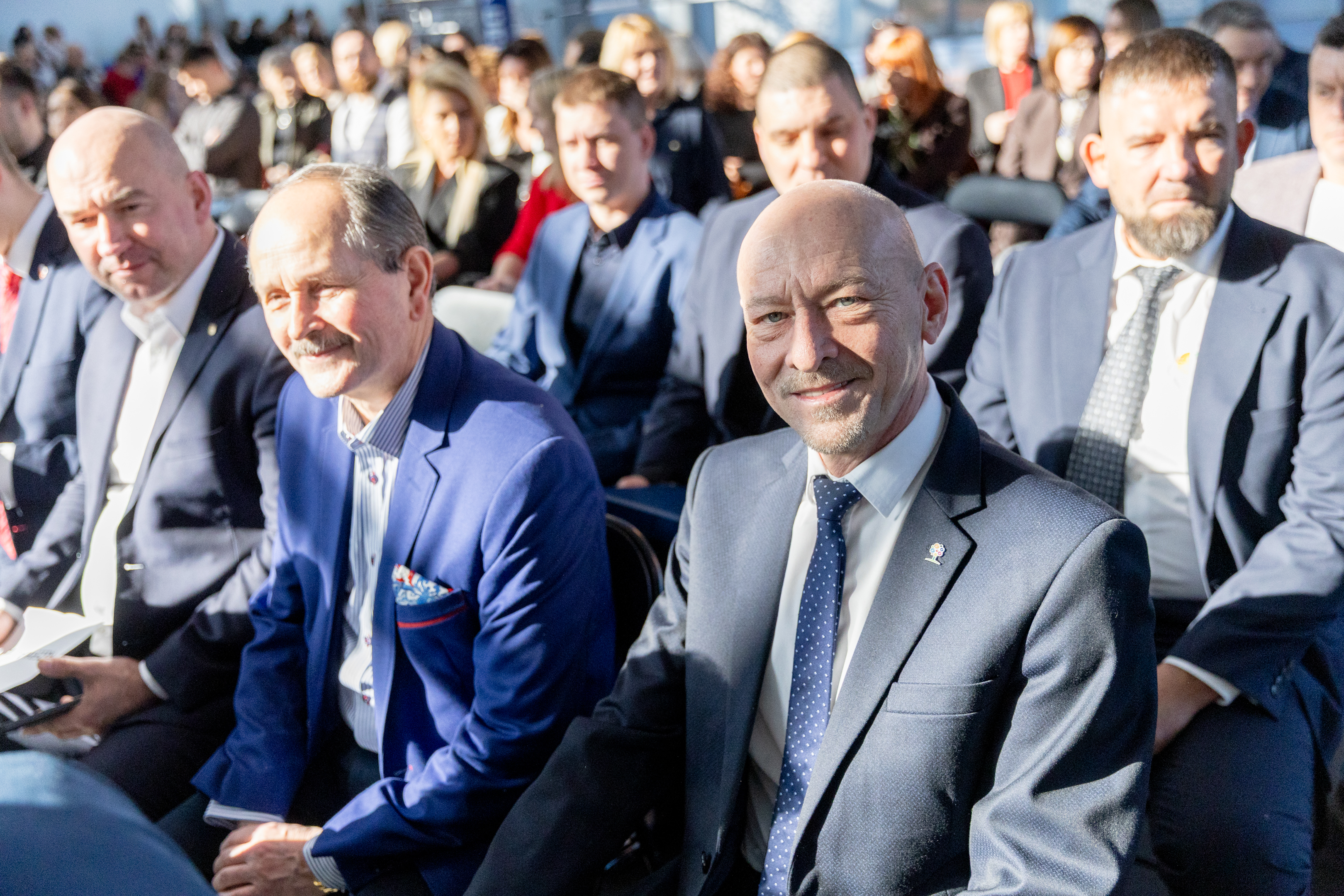 Mężczyźni w&nbsp;garniturach siedzą na&nbsp;krzesłach