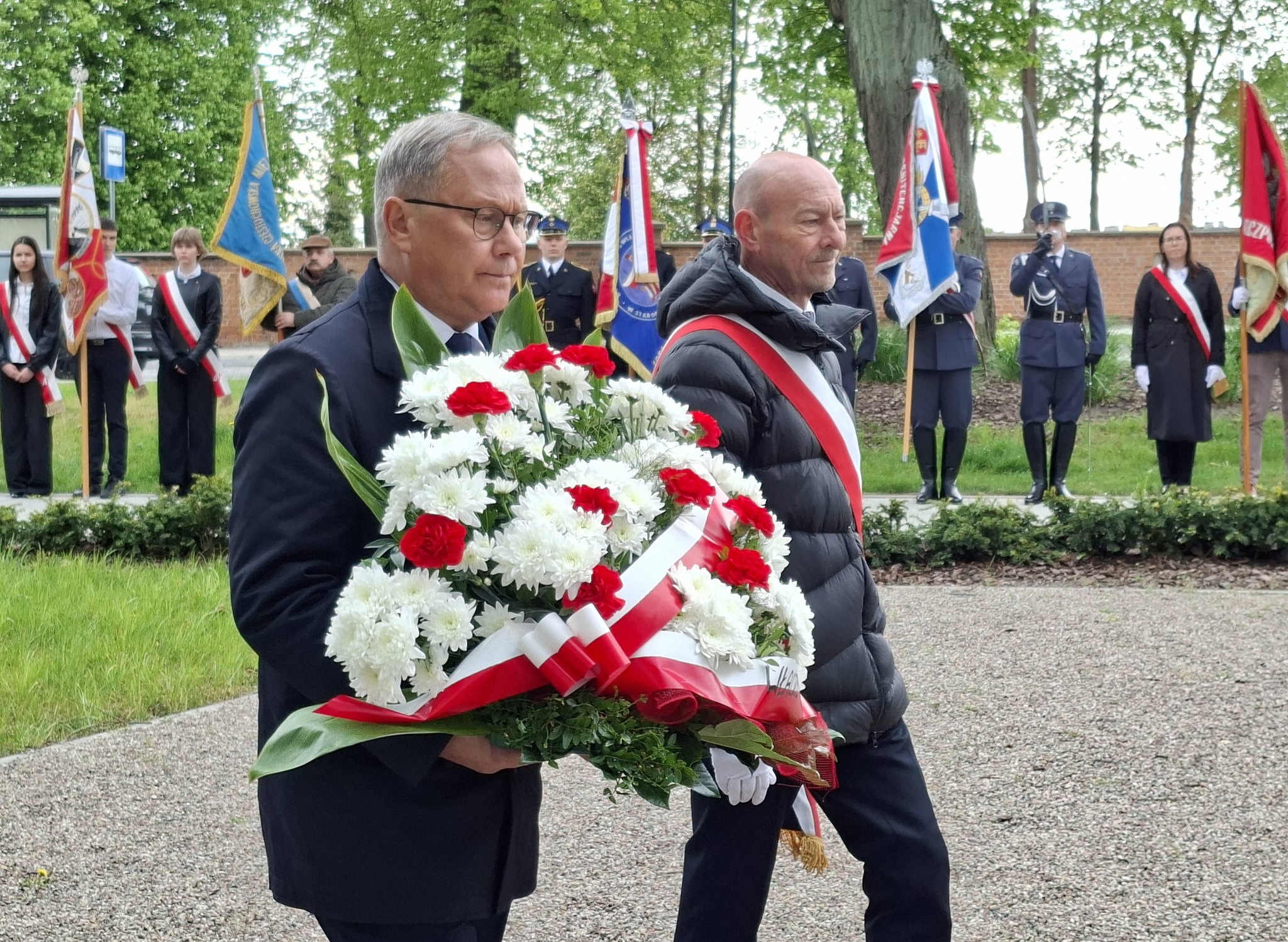 Dw&oacute;ch mężczyzn składa kwiaty.