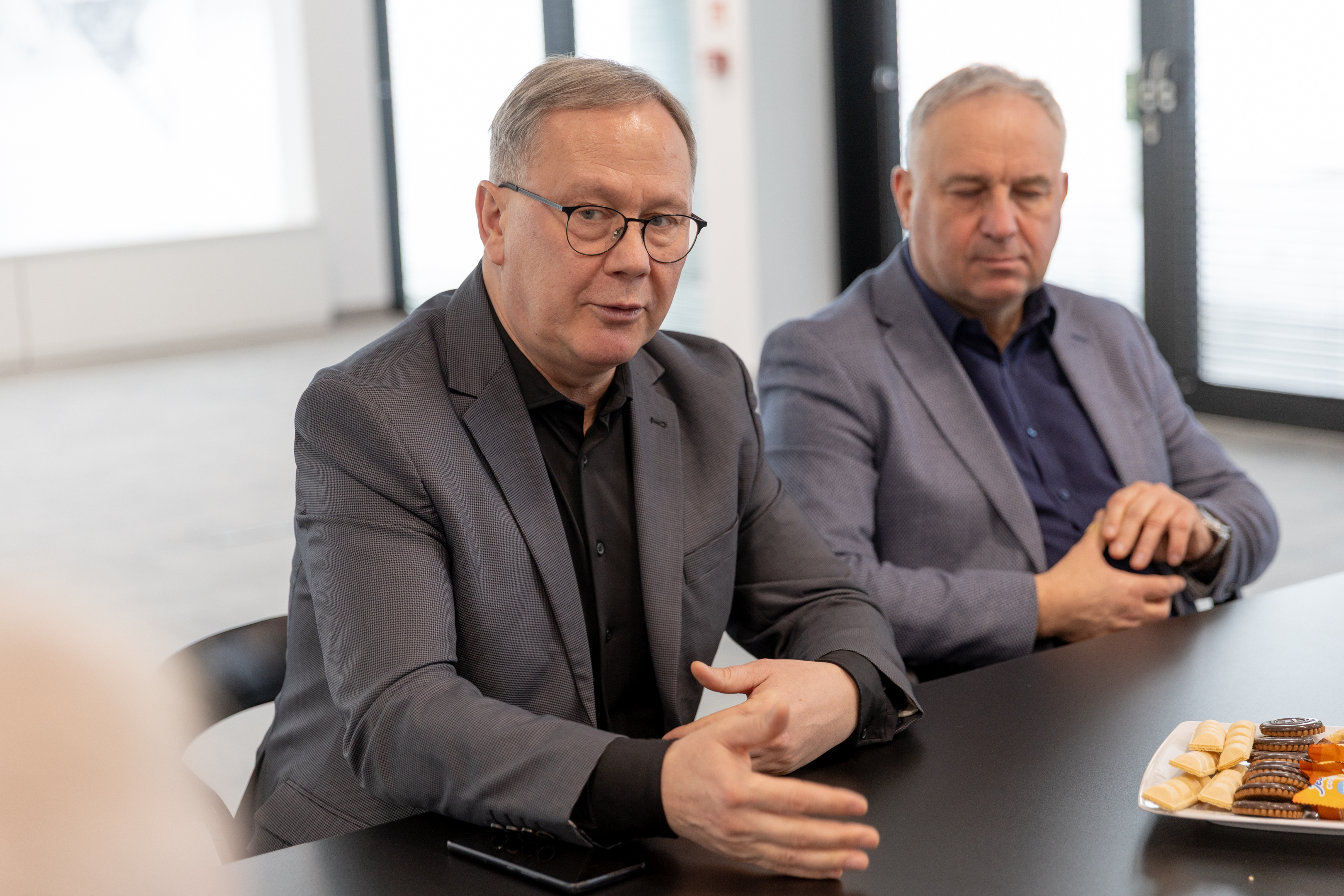 dwoch mężczyzn w&nbsp;garniturach przy stole