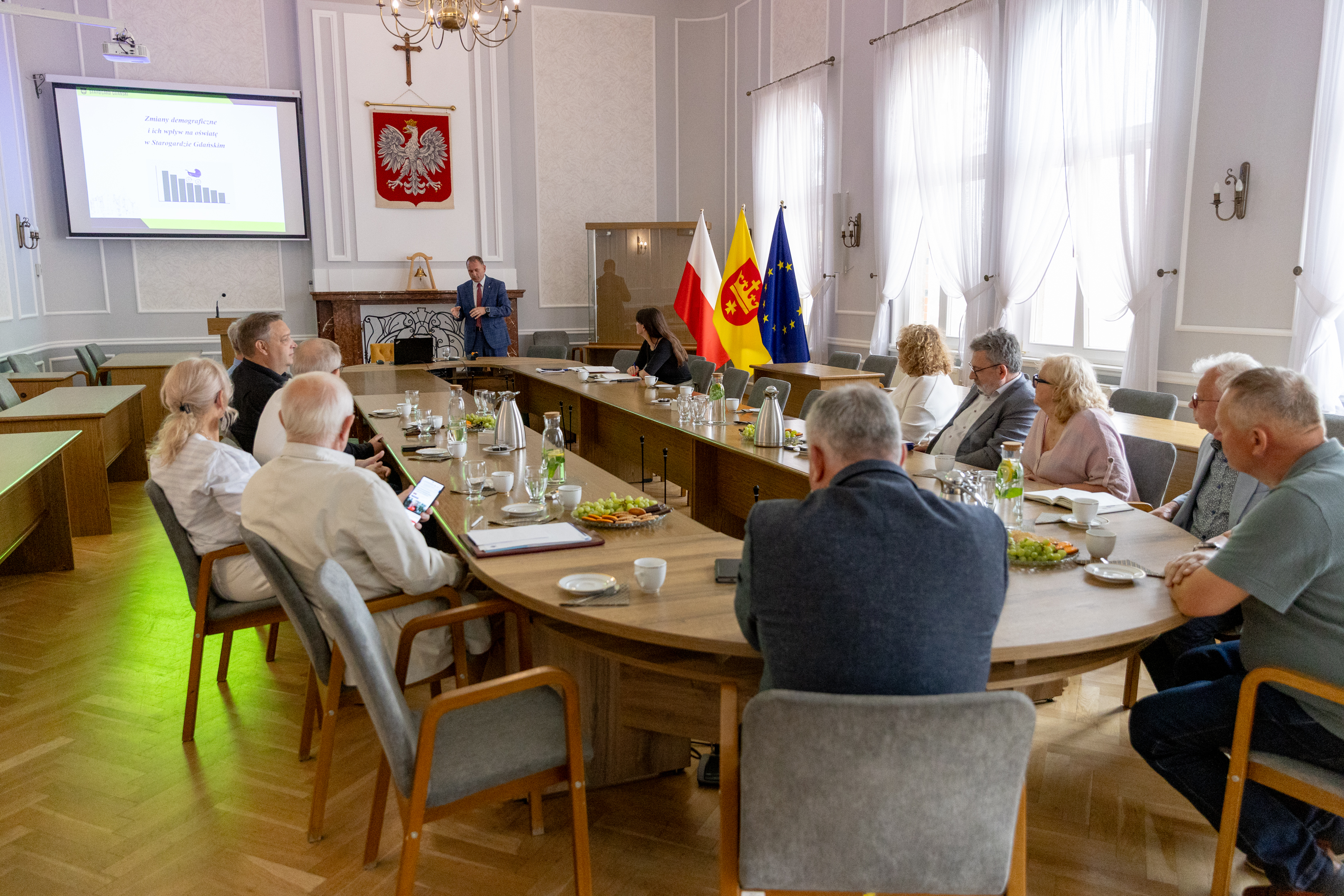 Ludzie siedzą przy owalnym stole i&nbsp;obradują 