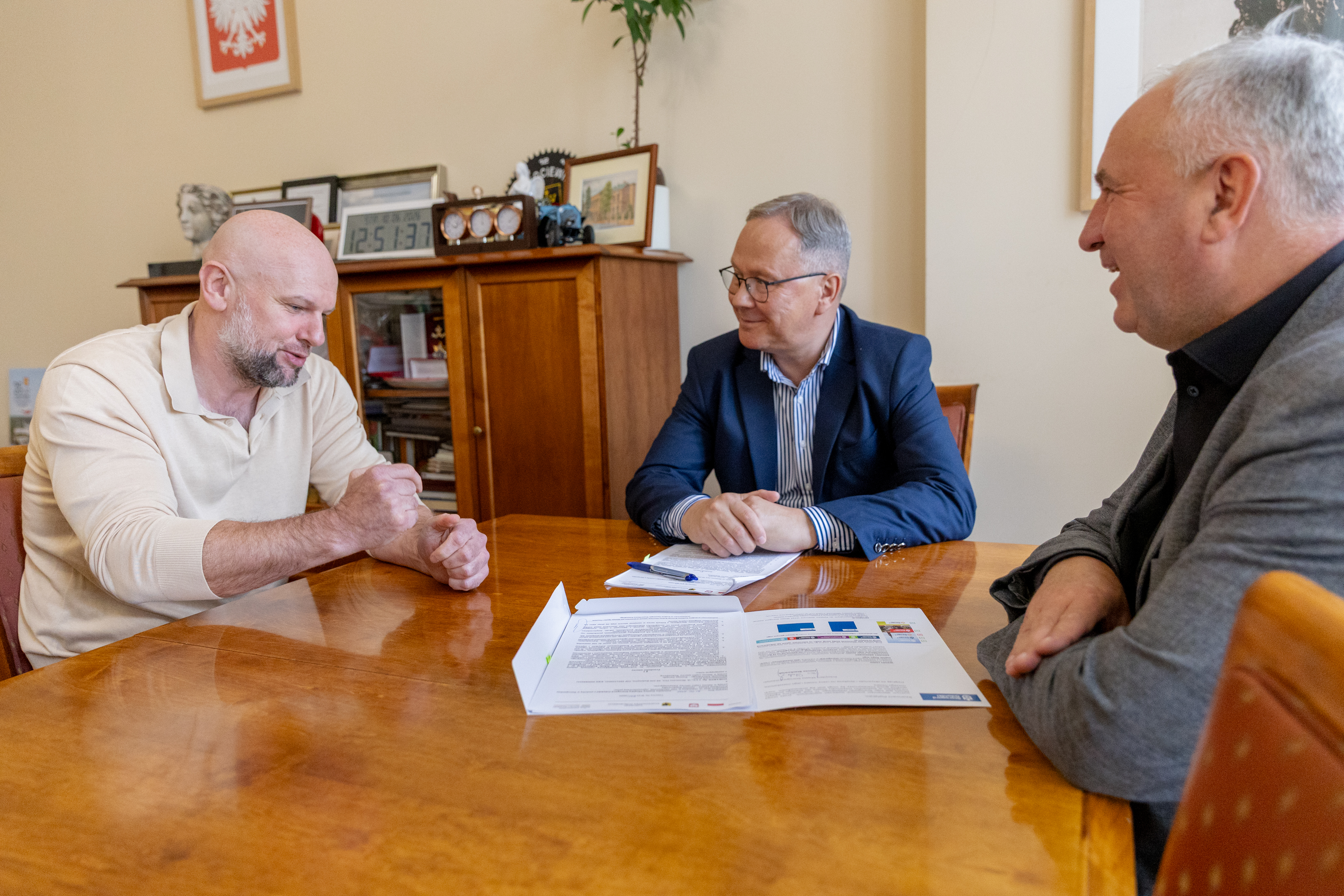 trzech mężczyzn siedzi przy stole rozmawia