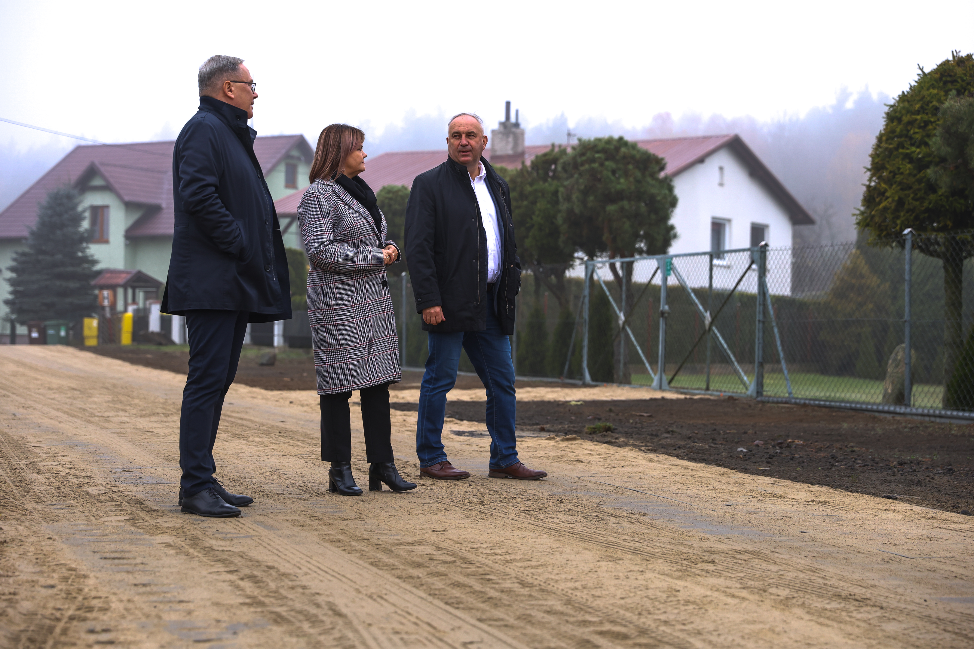Na ulicy utwardzonej płytami stoi dw&oacute;ch meżczyzn i&nbsp;kobieta