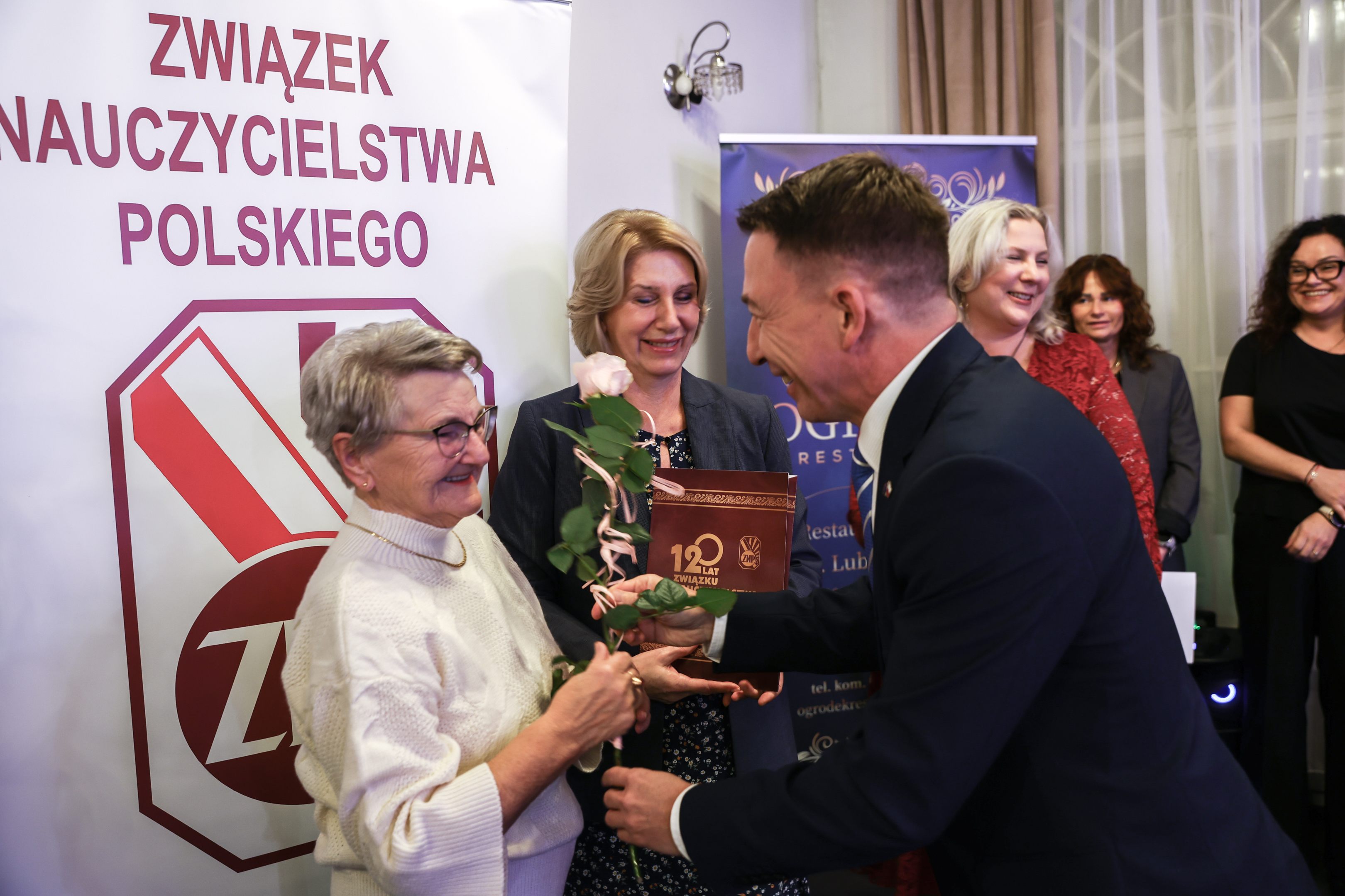 Starsza Pani odbiera gratulacje z&nbsp;rak mężczyzny 