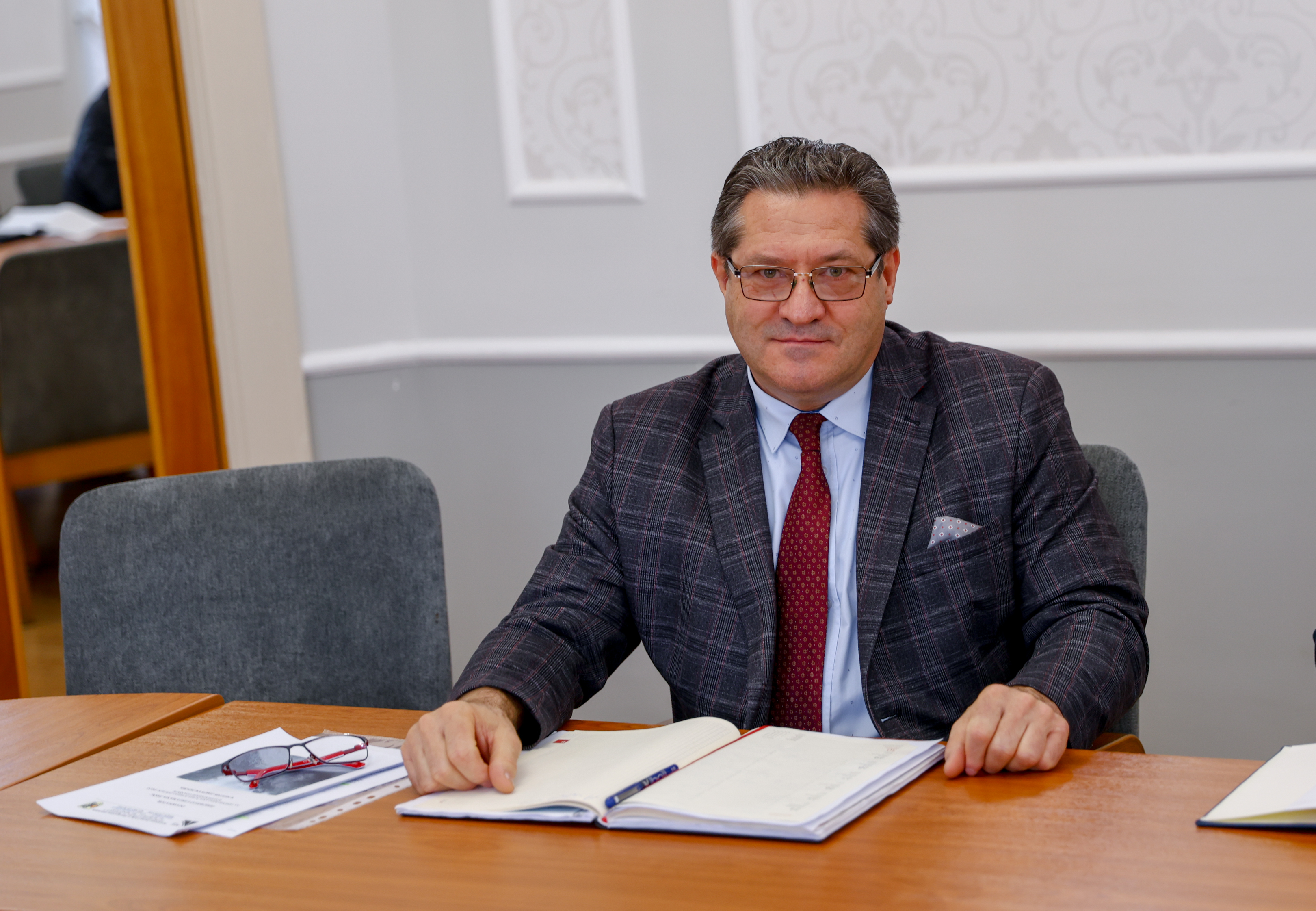 Mężczyzna w&nbsp;garniturze siedzi przy stole