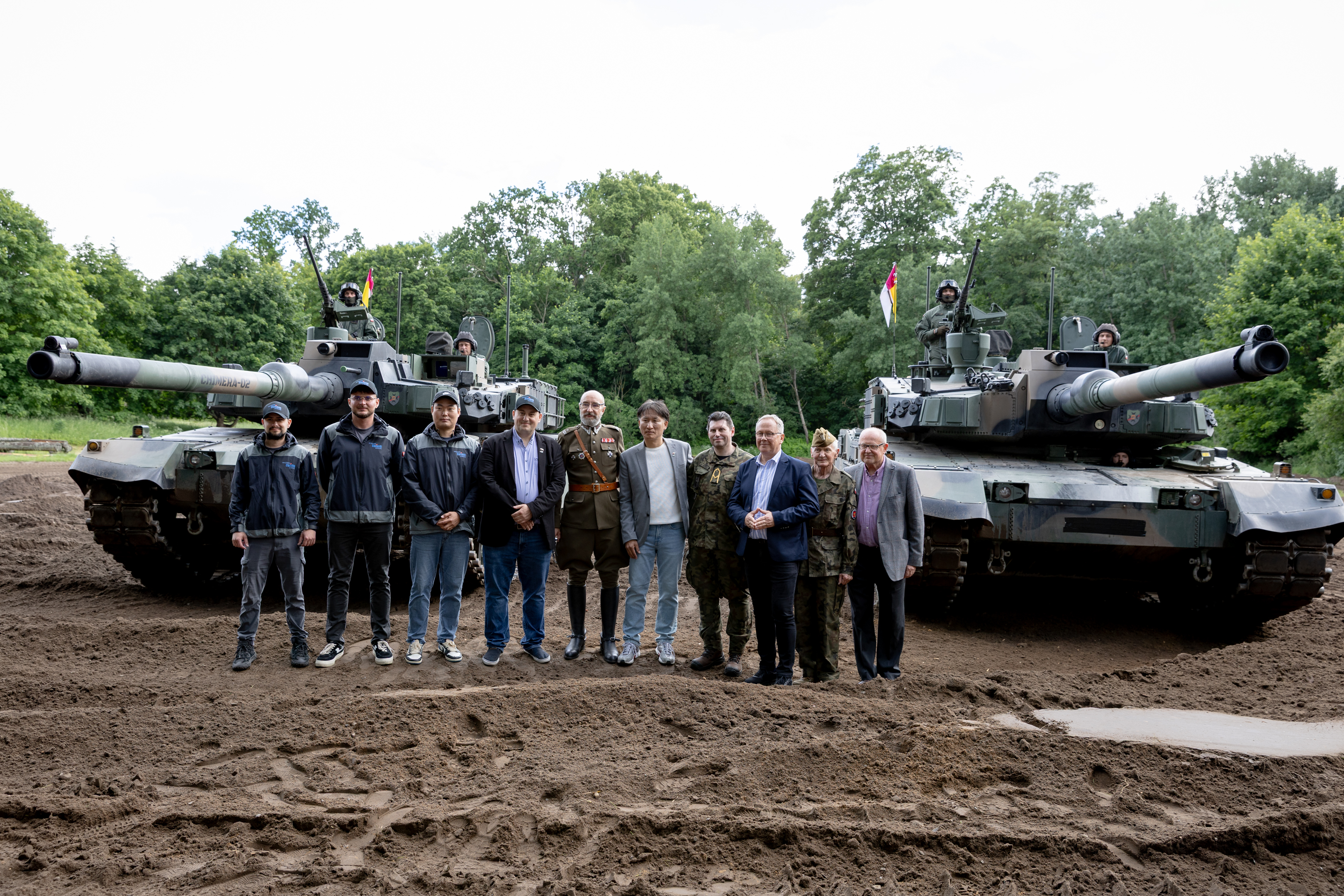 dwa czołgi i&nbsp;ludzie stojący przed nimi