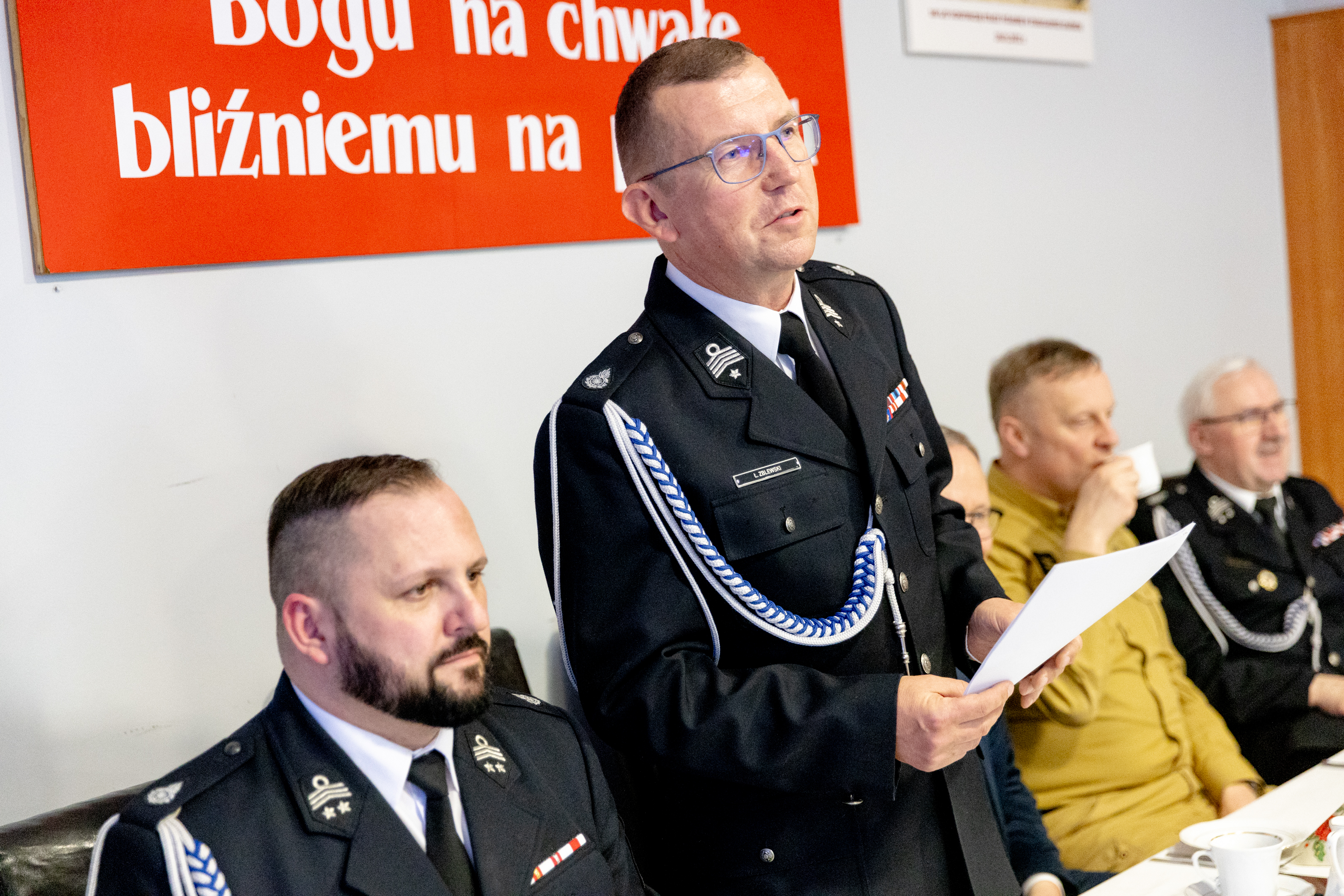 mężczyźni w&nbsp;mundurach strażak&oacute;w przy stole