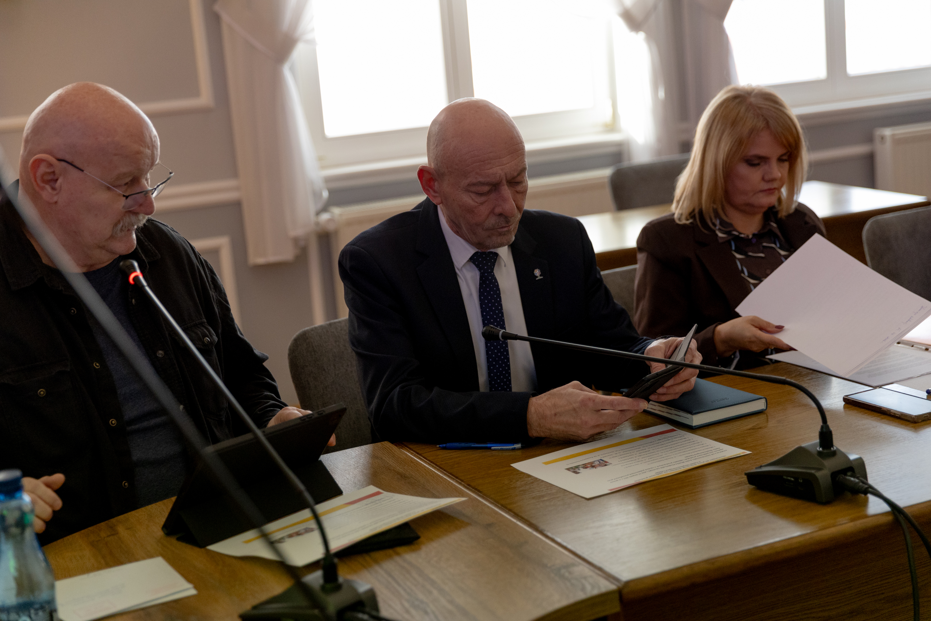 Dw&oacute;ch mężczyzn i&nbsp;kobieta siedzą przy stole obrad