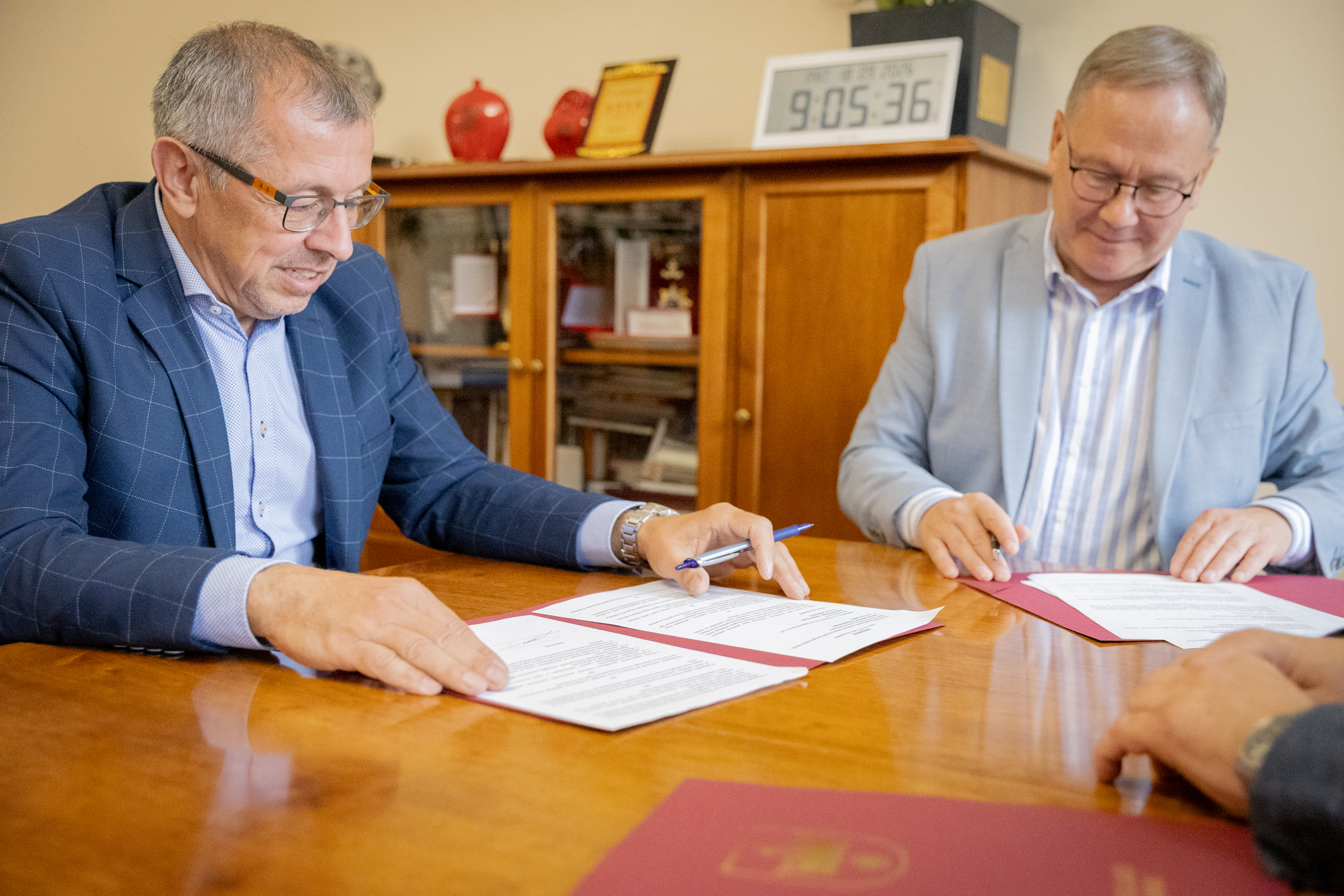 dw&oacute;ch mężczyn w&nbsp;garniturach przy stole podpisują porozumienie
