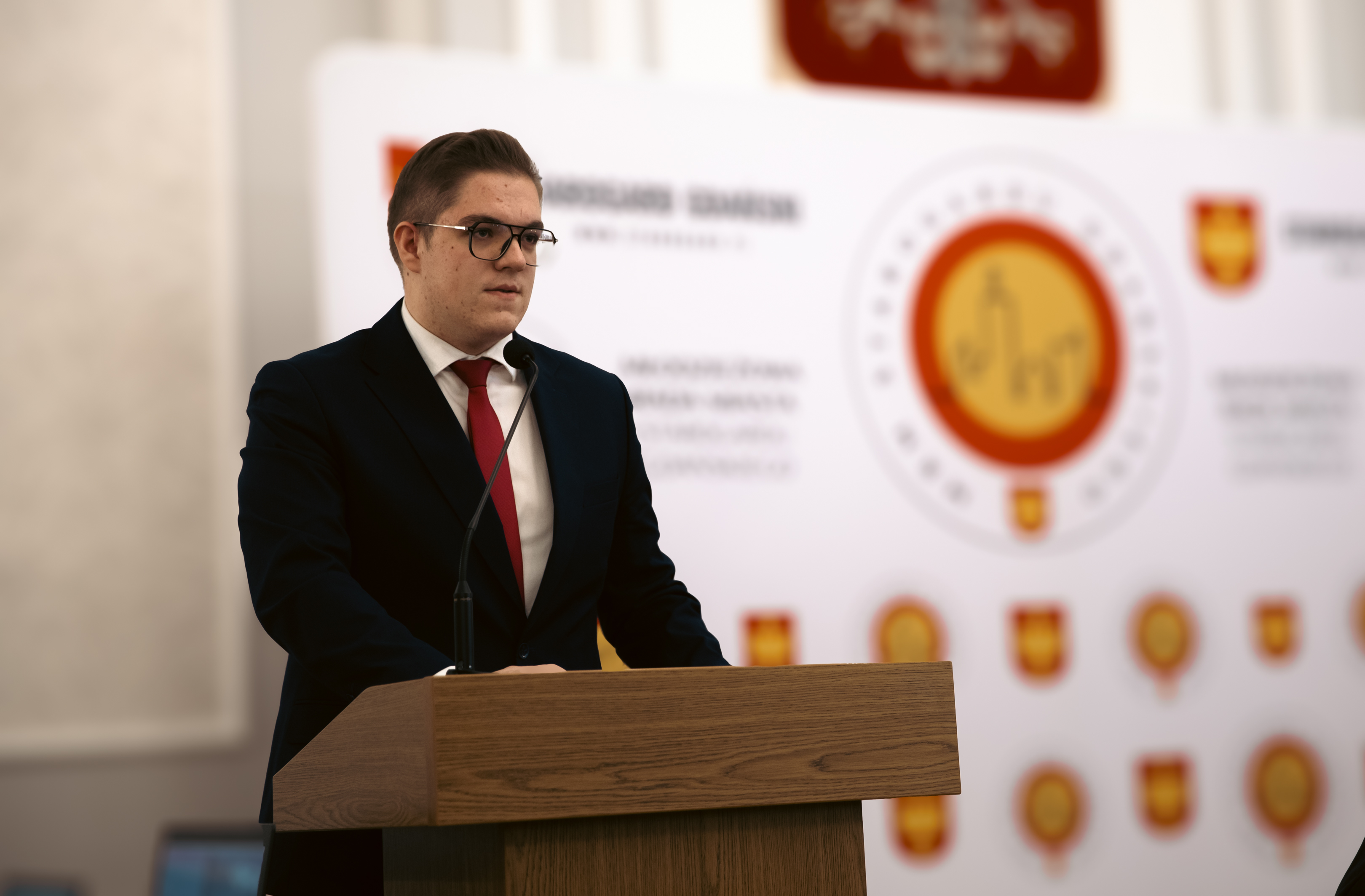 Mężczyzna w&nbsp;garniturze stoi przy m&oacute;wnicy