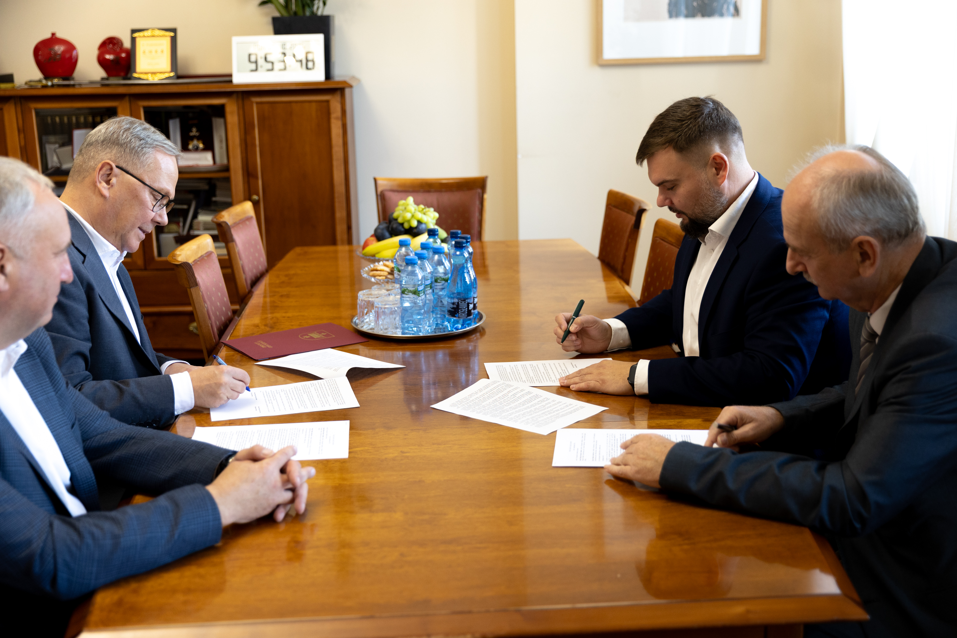 czterech mężczyzn w&nbsp;garniturach przy stole