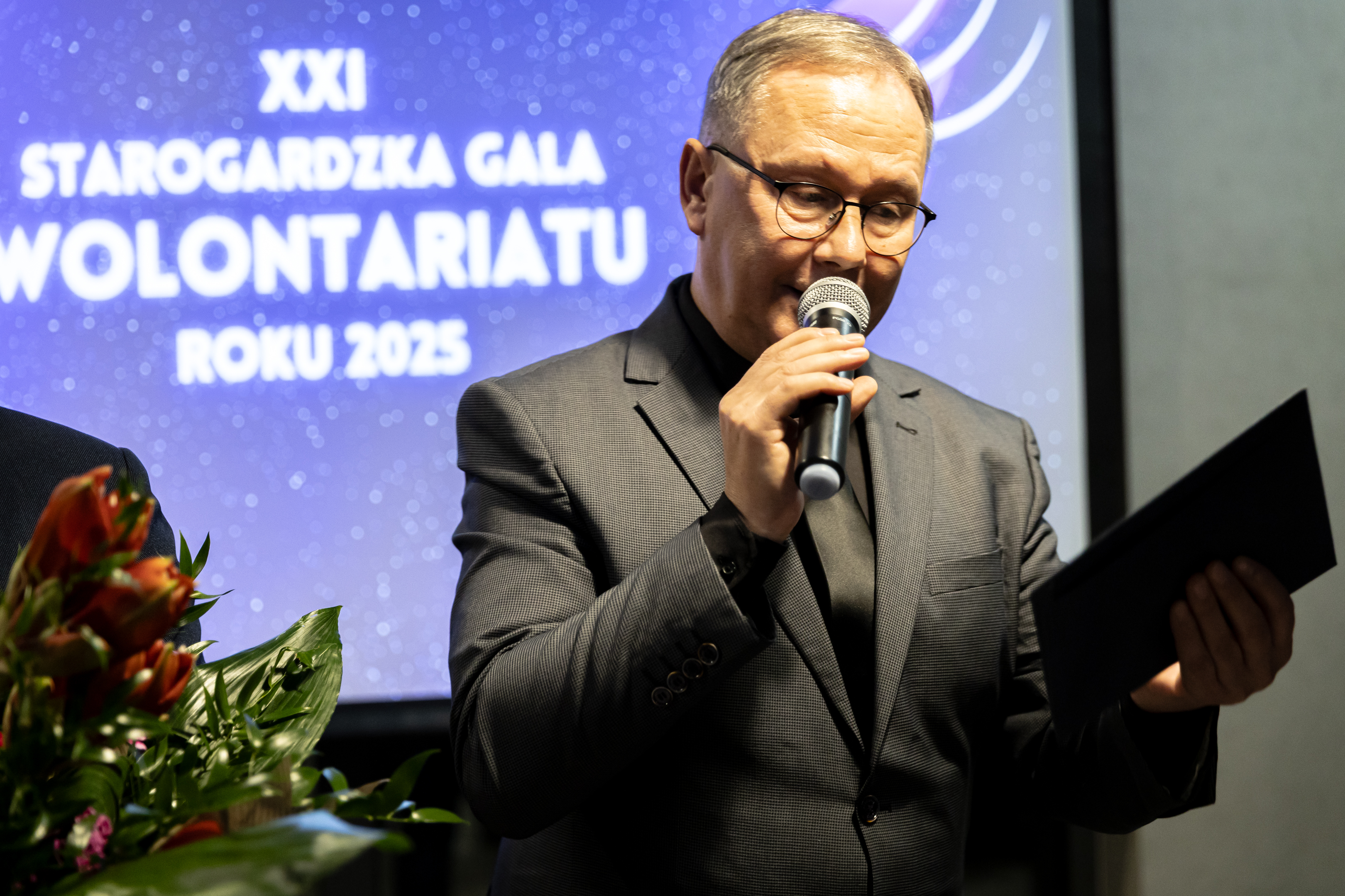 Mężczyzna w&nbsp;garniturze przy mikrofonie