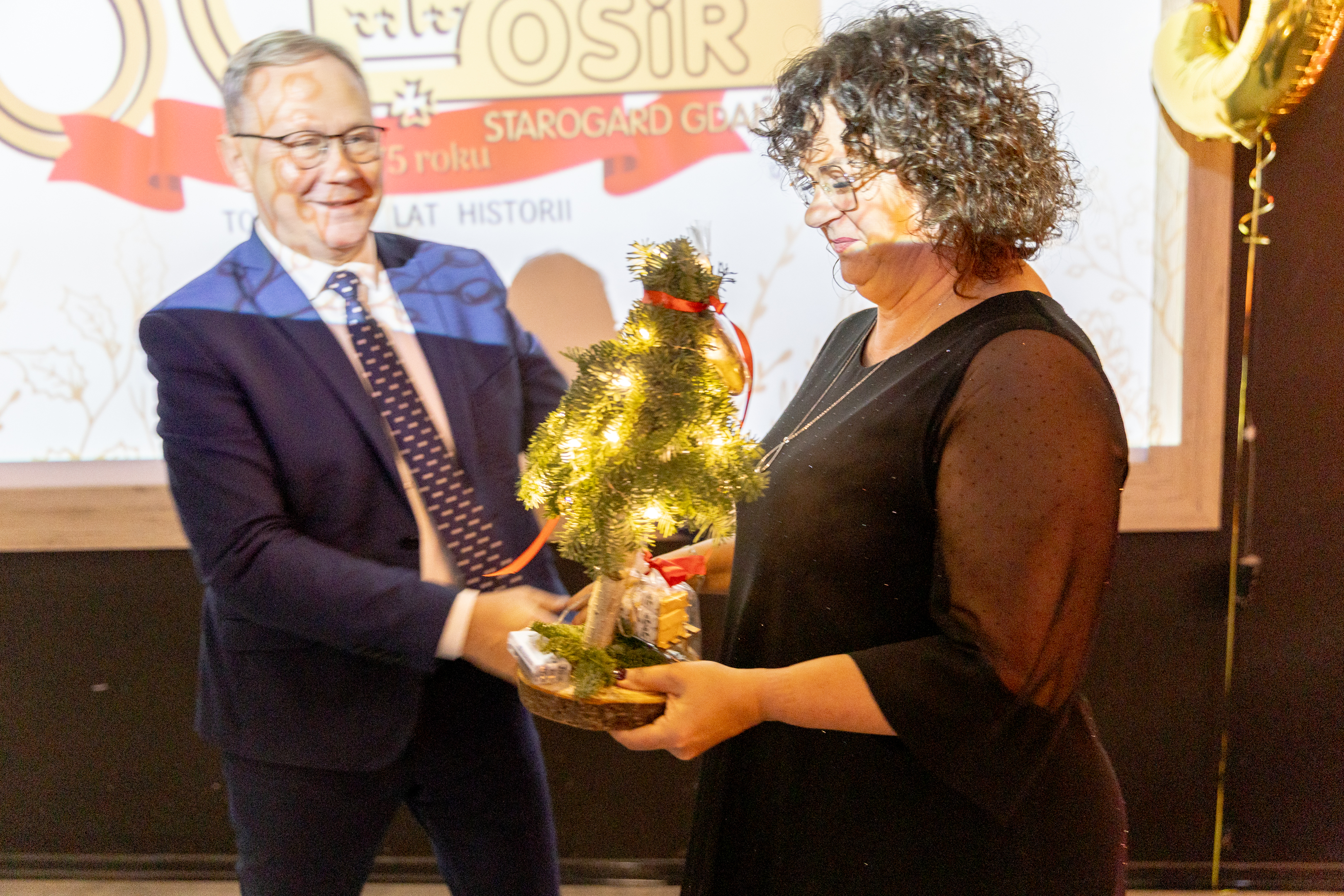 Mężczyna przekazuje kobiecie choinkę świąteczną