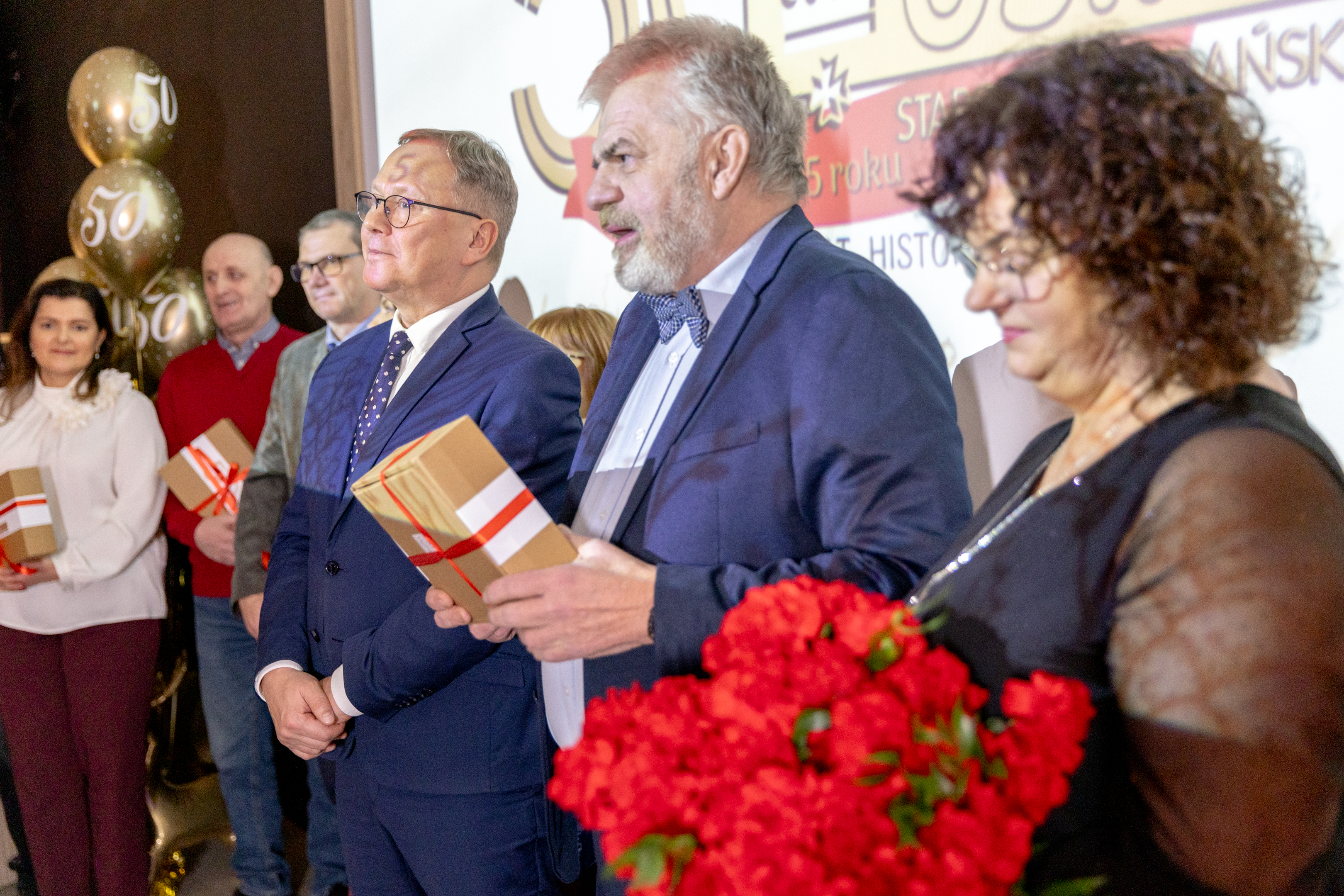 Dwoch mężczyzn w&nbsp;garniturach i&nbsp;kobieta w&nbsp;eleganckiej czarnej sukience