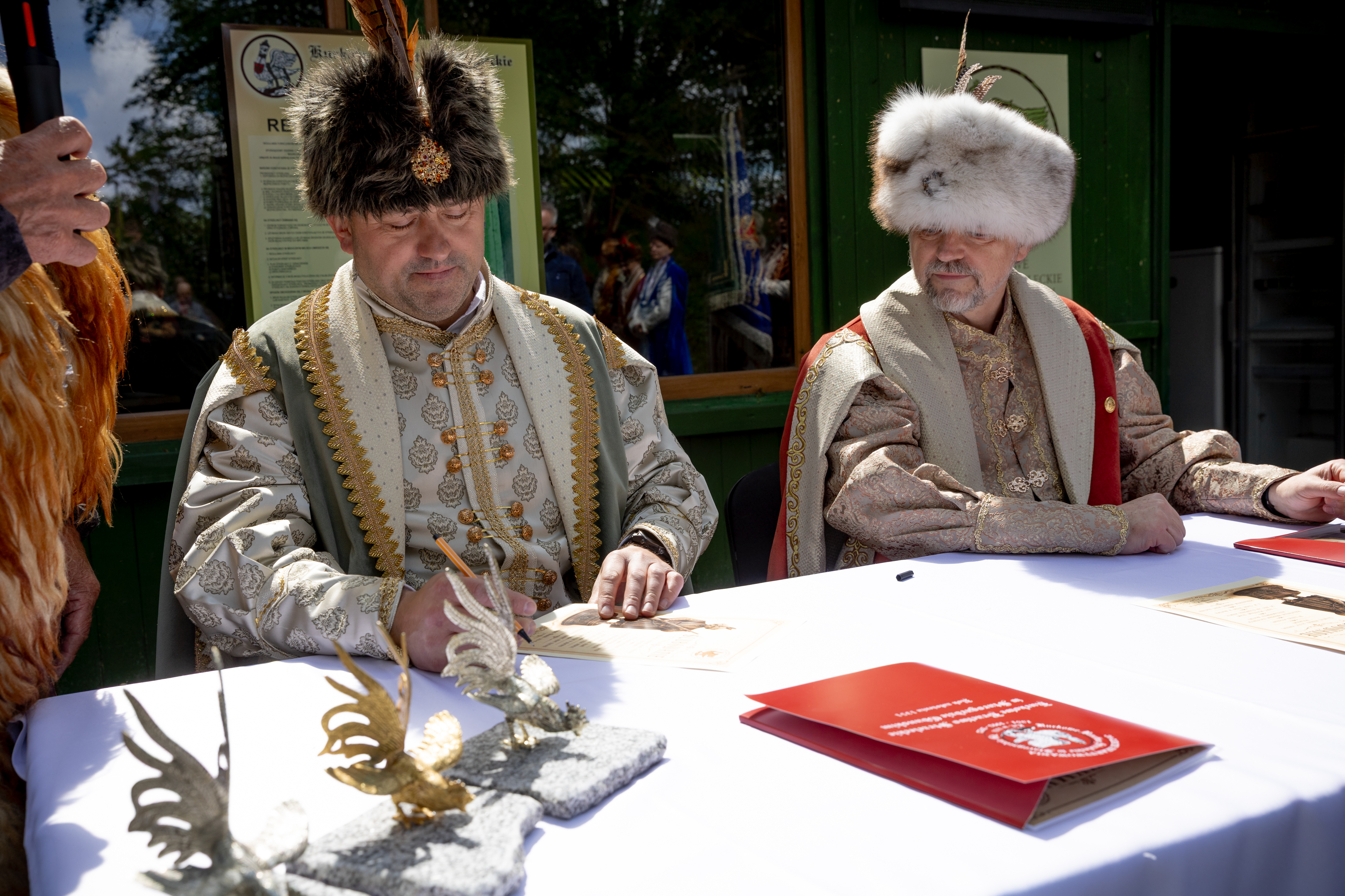 Dw&oacute;ch mężczyzn w&nbsp;strojach Braci Kurkowych podpisuje deklarację przynależności do Bractwa
