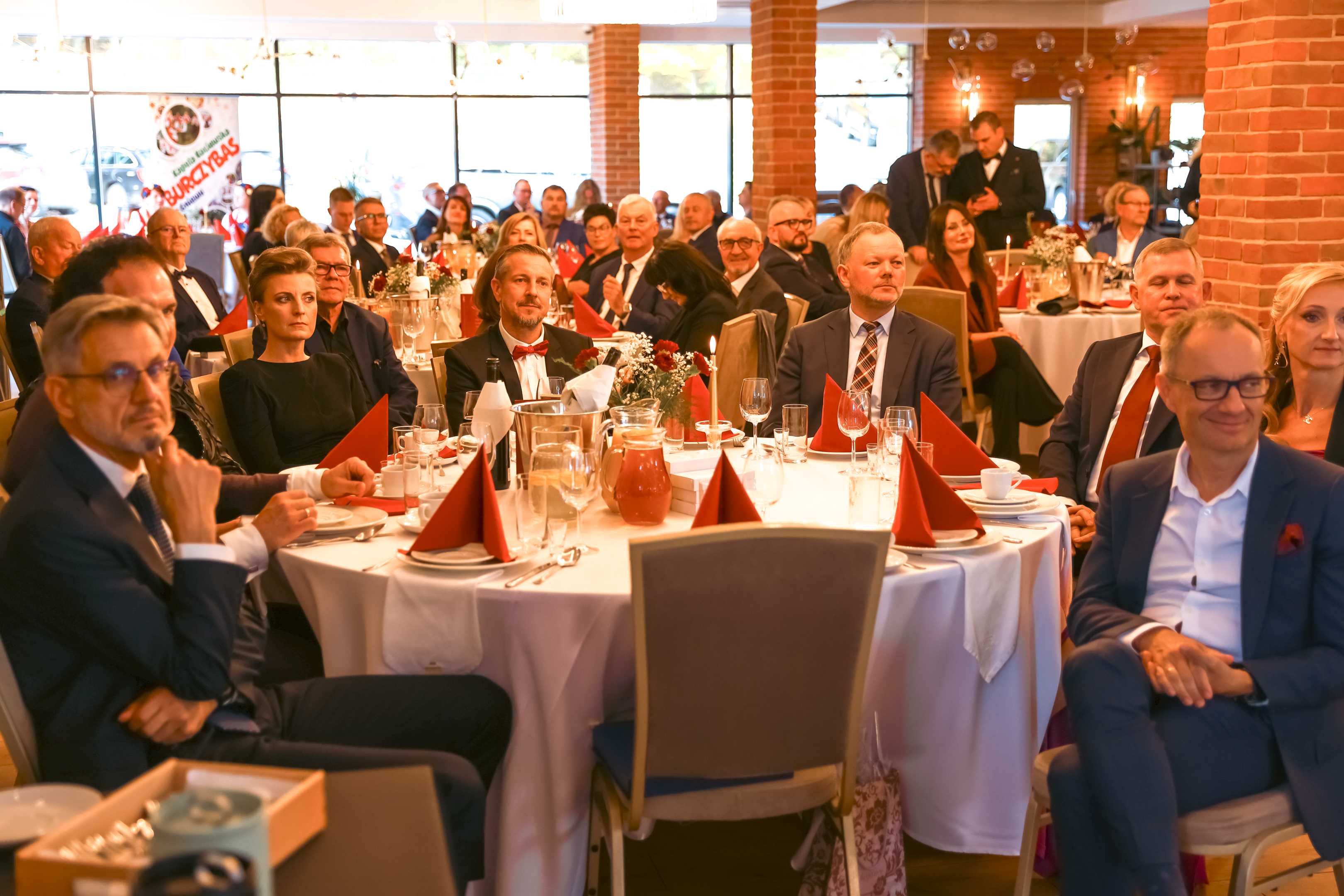 wiele gości w&nbsp;garniturach siedzi przy okrągłym stole