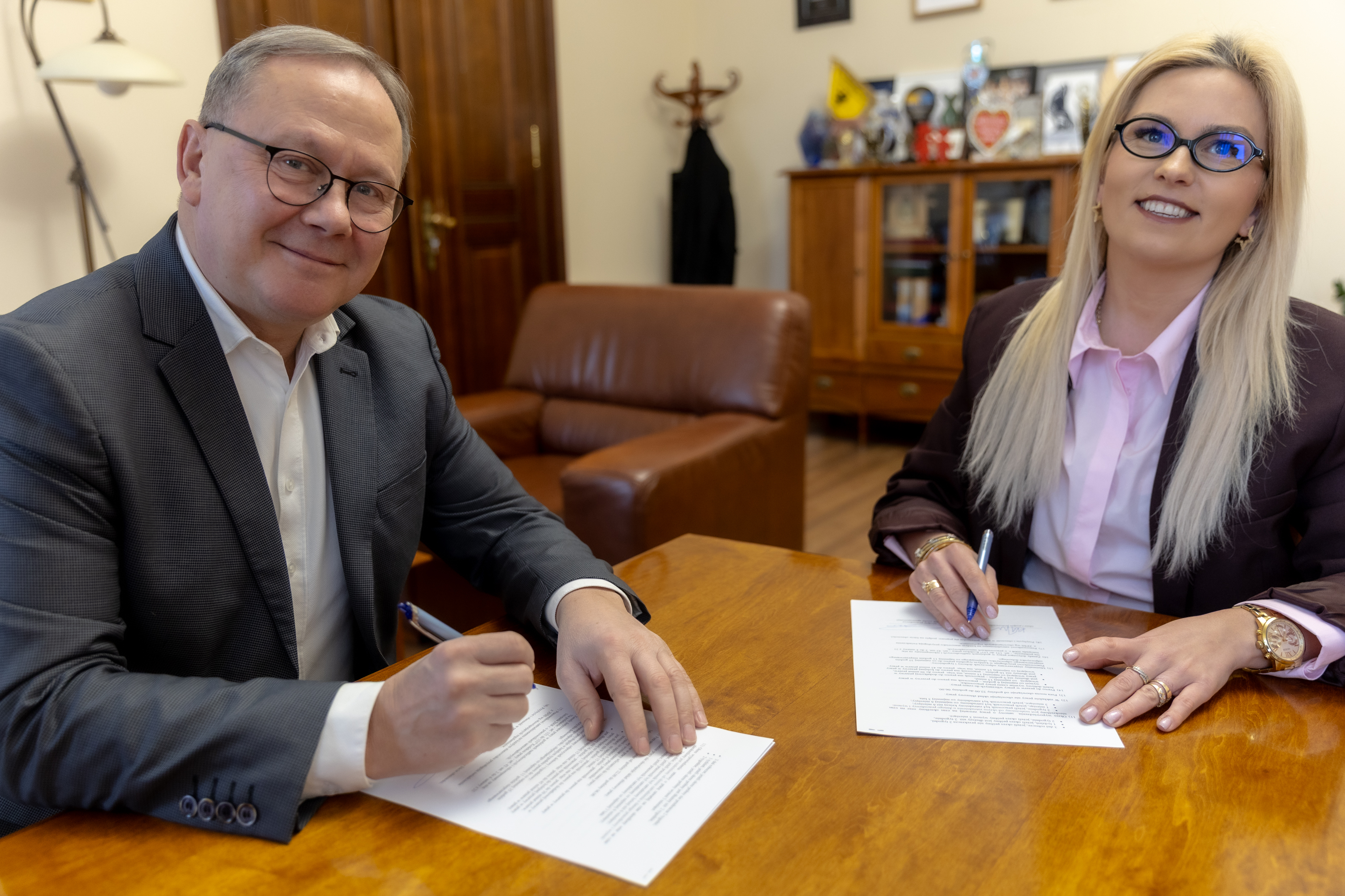 Mężczyzna i&nbsp;kobieta przy stole podpisują dokumenty