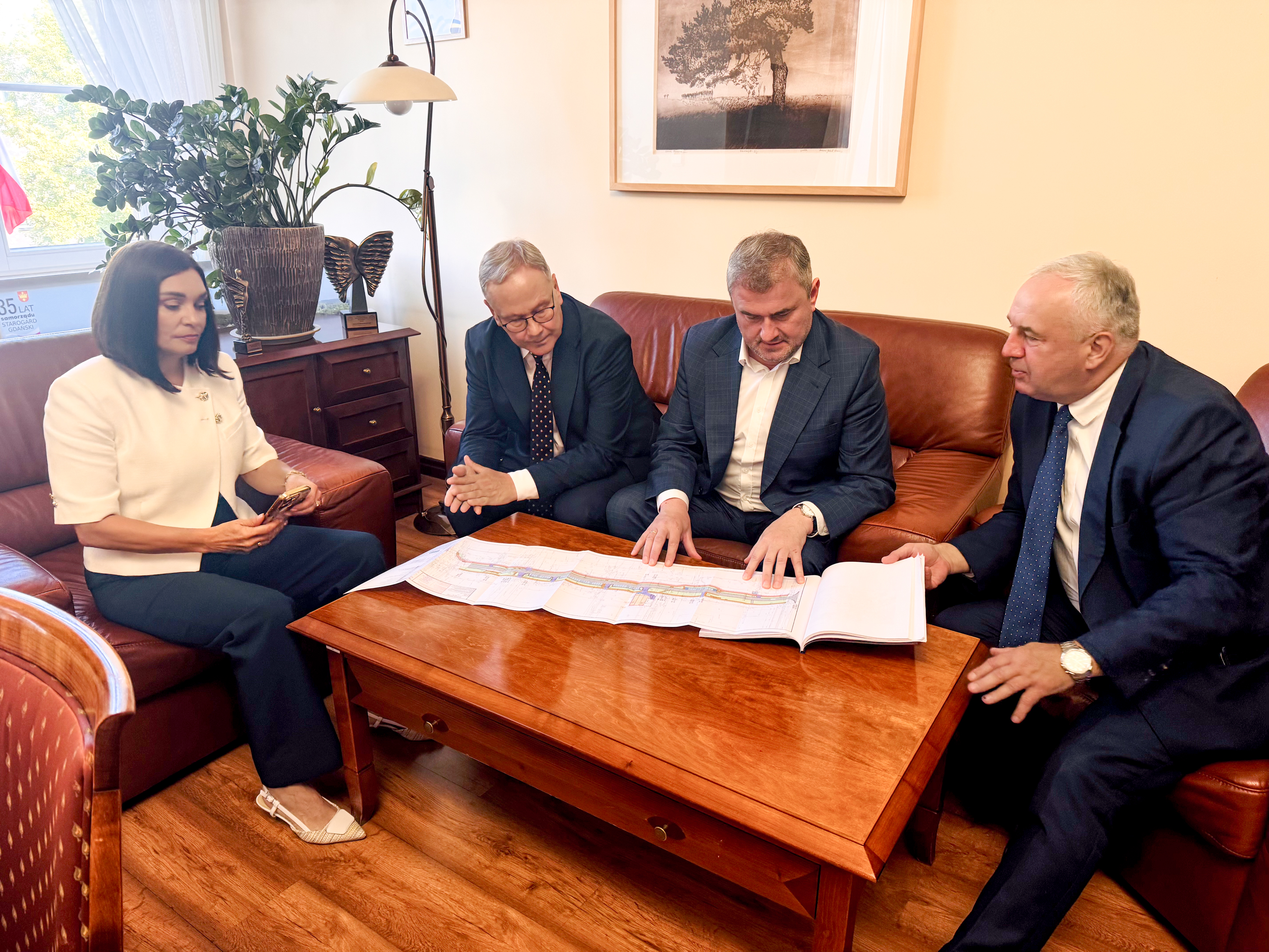czterech mężczyn i&nbsp;jedna kobieta siedzą przy stole i&nbsp;oglądają projekt ulicy