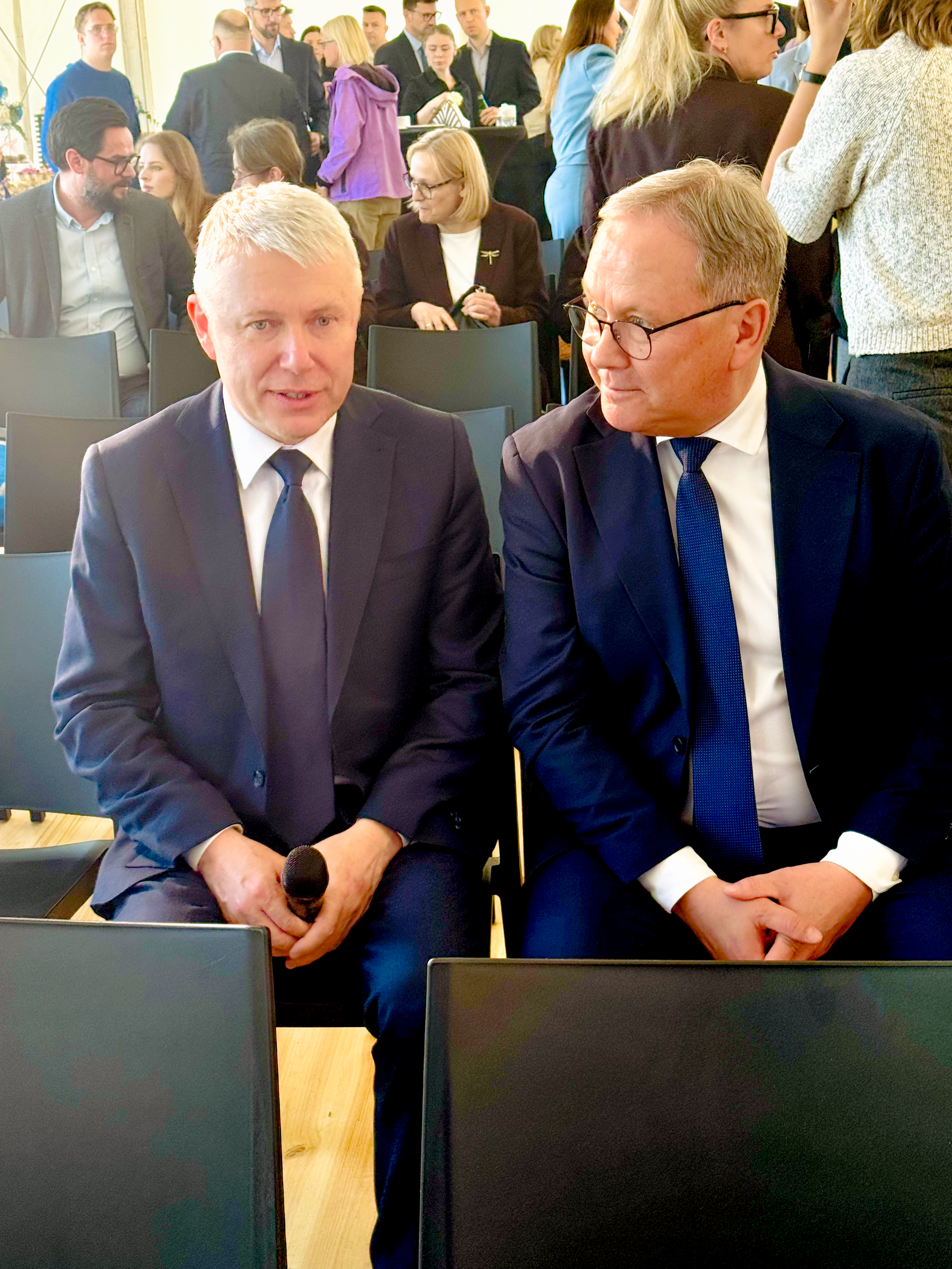 dw&oacute;ch mężczyzn w&nbsp;garniturach siedzi na&nbsp;krzesłach i&nbsp;rozmawia