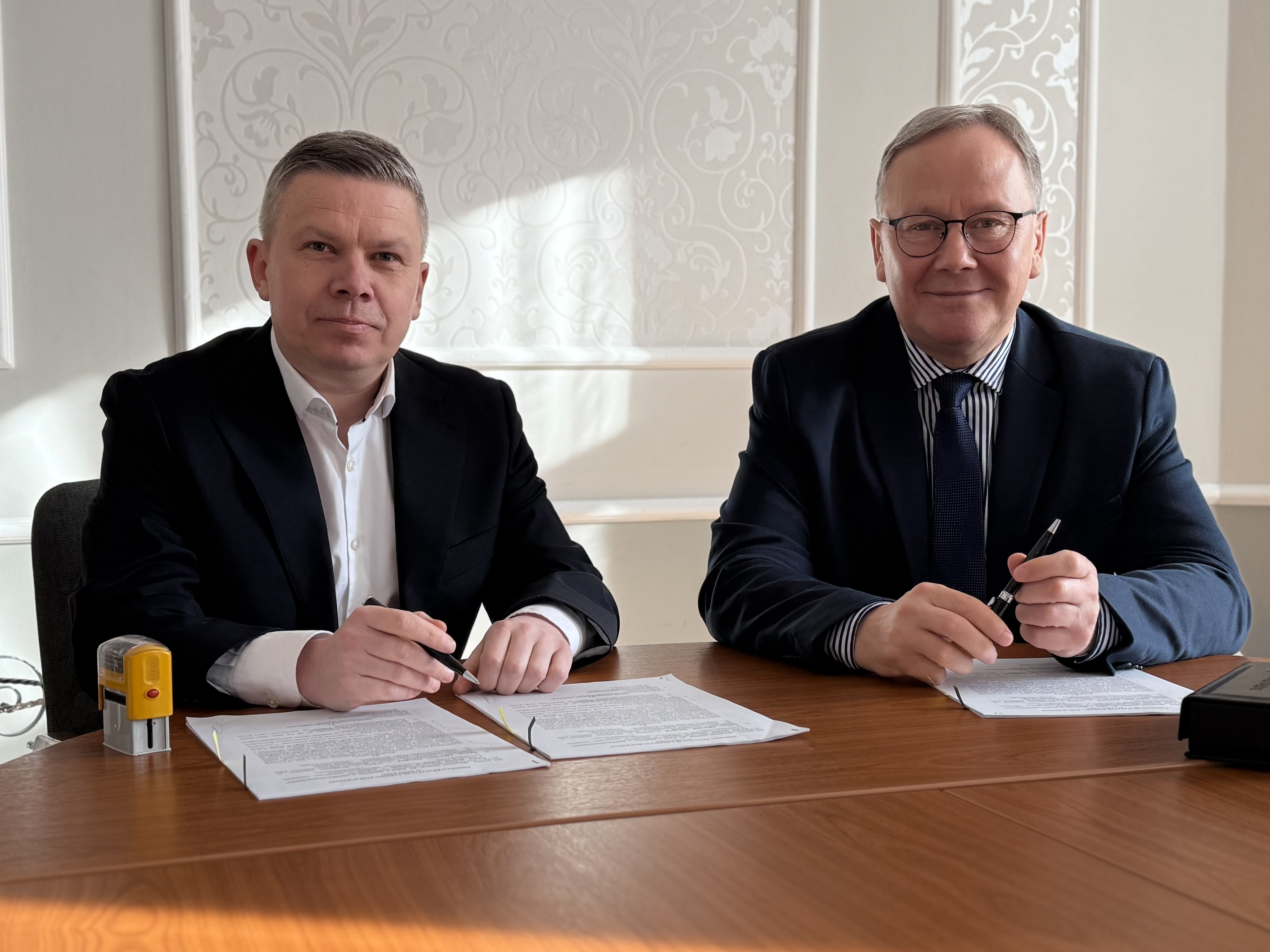 Dw&oacute;ch mężczyzn siedzi przy stole.