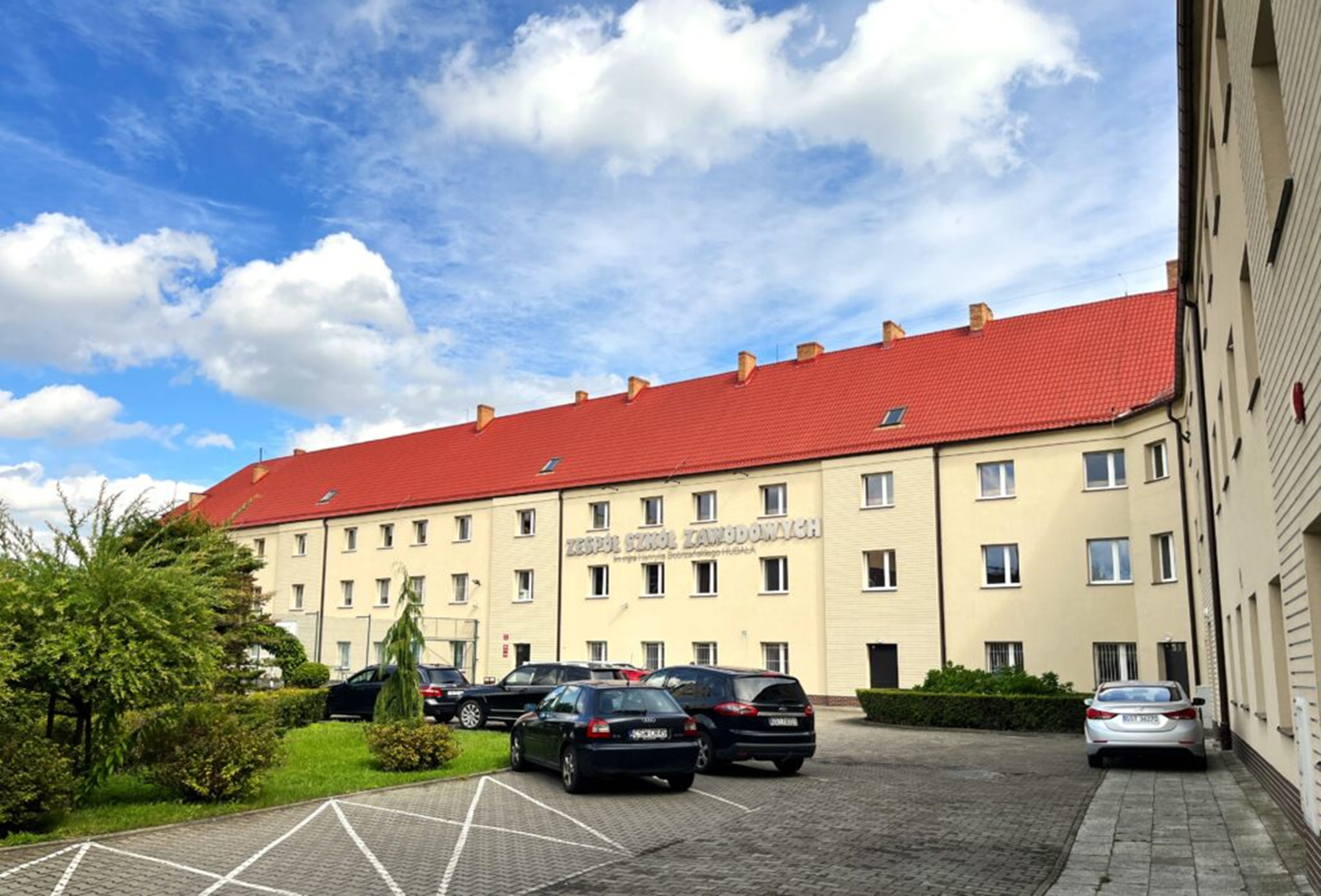 Beżowy budynek z&nbsp;czerwona dach&oacute;wką.