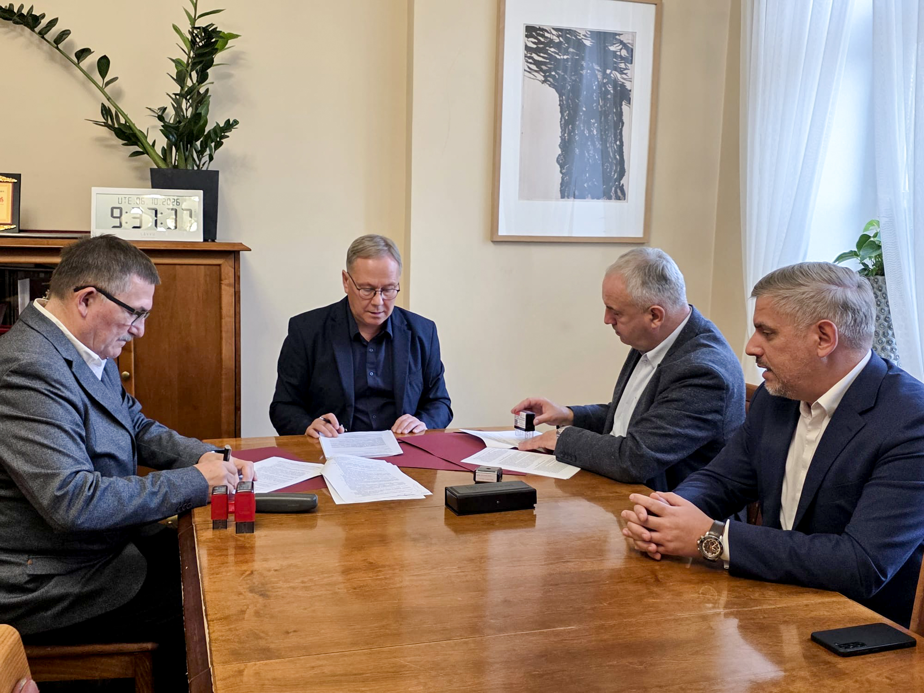 czterech mężczyzn przy stole podpisuje dokumenty