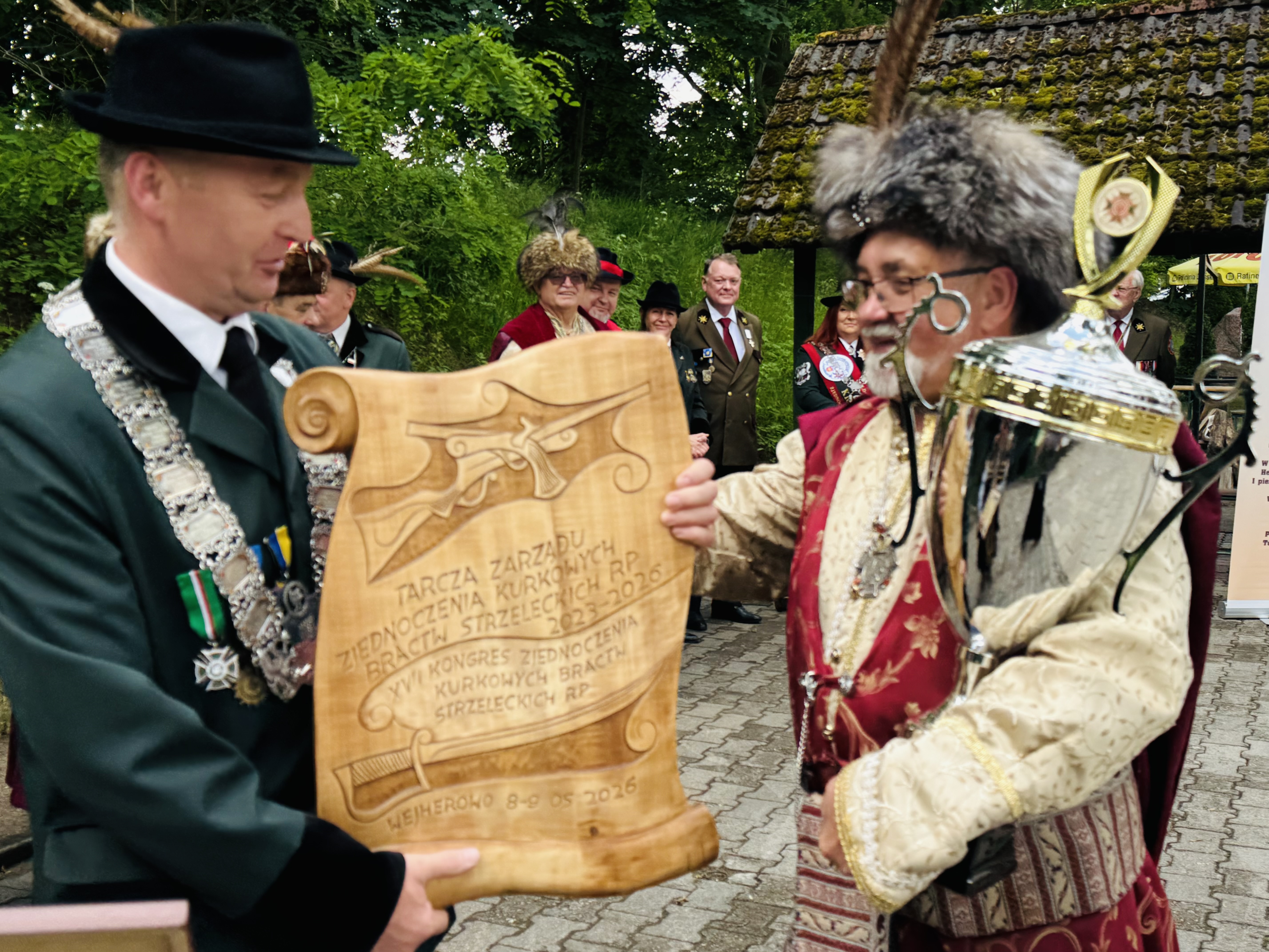 Dw&oacute;ch mężczyzn w&nbsp;strojach bractwa . jeden odbiera nagrodę