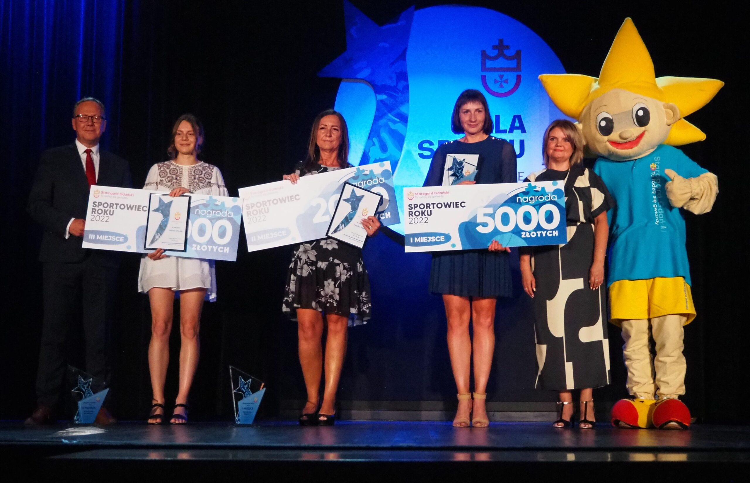 Nagrodzone w kategorii Sportowiec Roku 2022 w Starogardzie Gdańskim, od lewej: pięcioboistka Wiktoria Wierzba (SPP CWKS Legia Warszawa - III miejsce), koszykarka Angelika Wanta (WKSN Świt Wrocław - II miejsce, nagrodę odebrała mama) oraz triathlonistka Magdalena Lenz (Stowarzyszenie TRI Starogard Gdański - I miejsce) z Prezydentem Miasta Januszem Stankowiakiem, Przewodniczącą Rady Miasta Anną Benert oraz starogardzką maskotką Gwiazdkiem.