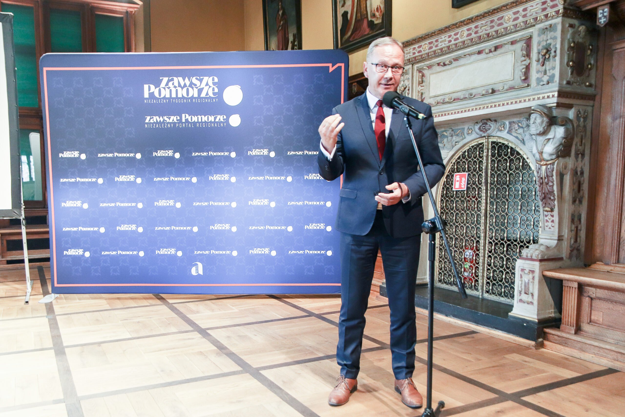 Mężczyzna w garniturze stoi przy mikrofonie
