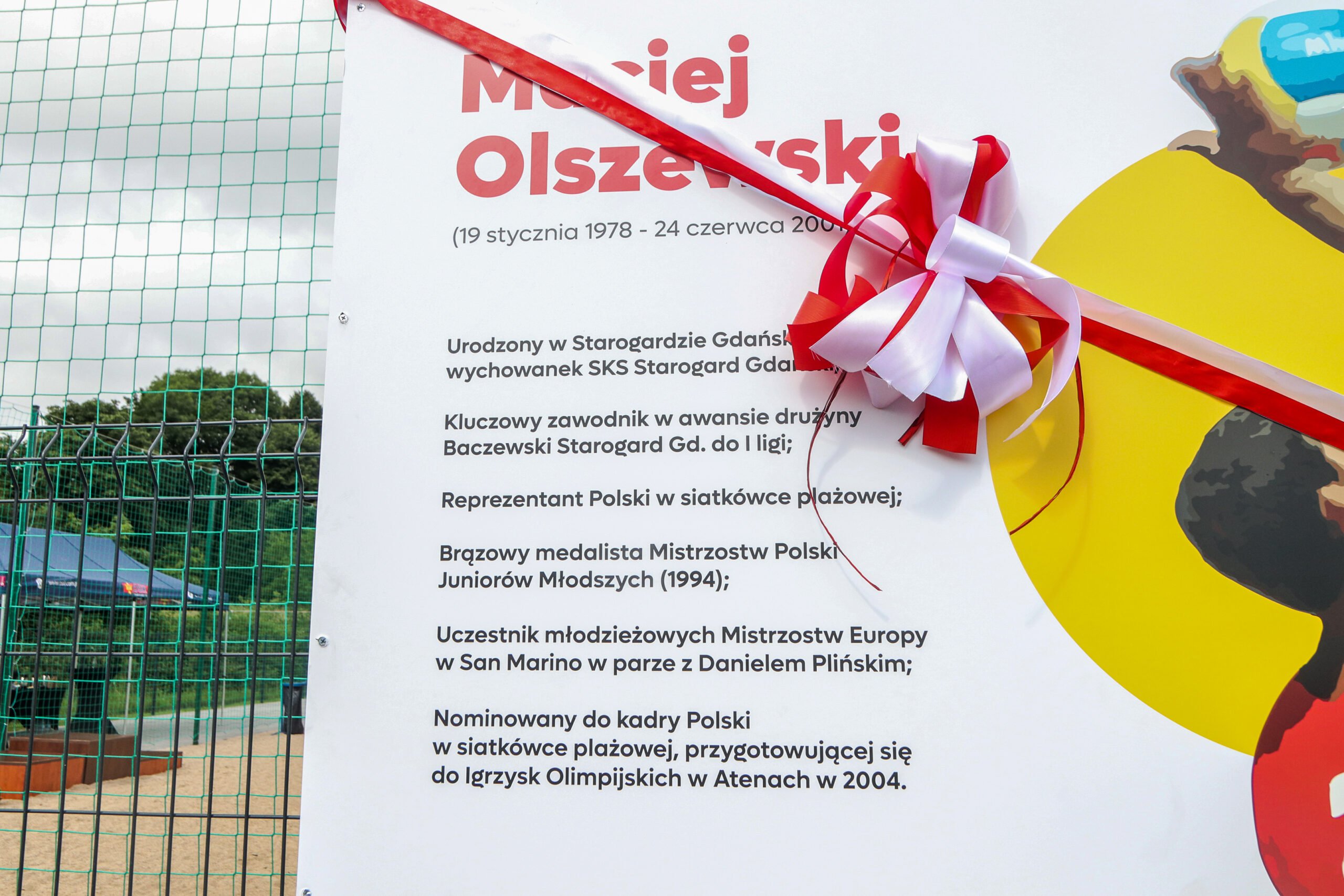 tablica upamiętniajaca Macieja Olszewskiego przewiazana czerwonąwstęgą