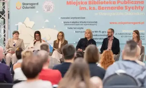 Dyrektorzy, nauczyciele, władze miasta siedzą na scenie.