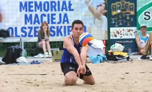 Siatkarz odbija piłkę na piasku.