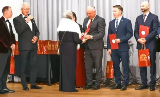 Męzczyzna w garniturze odbiera nagrode z rak kobiety w eleganckiej sukni