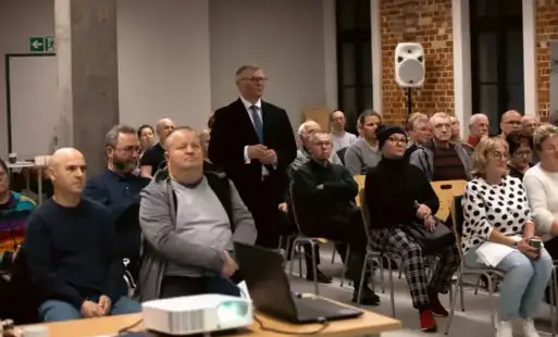 Ludzie na sali po srodku stoi mezczyzna 