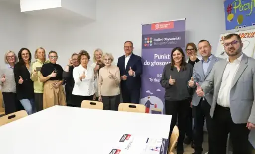 Ludzie stoją wokół Prezydenta Miasta z wyciągnietym kciukiem w góre i uśmiechami na twarzach
