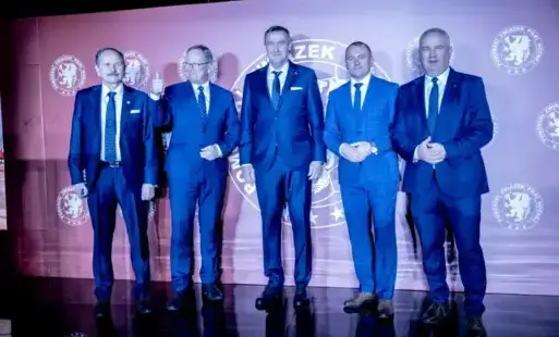 Pięciu mężczyzn w garniturach stoi na scenie 