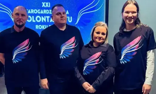 Dwóch mężczyzn i dwie kobiety w koszulkach czarnych z niebiessko rózowymi skrzydłami
