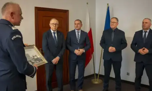 Mężczyzna z w mundurze policyjnym stoi twarza do czterech mężczyzn w garniturach