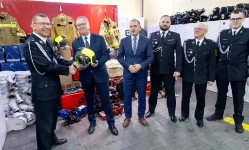 5 męzczyzn w mundurach strażackich i dwoch w garniturach, uścisk dłoni