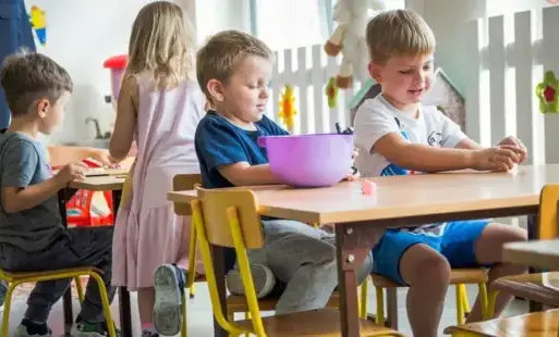 dzieci przy stoliczku bawią się plasteliną 