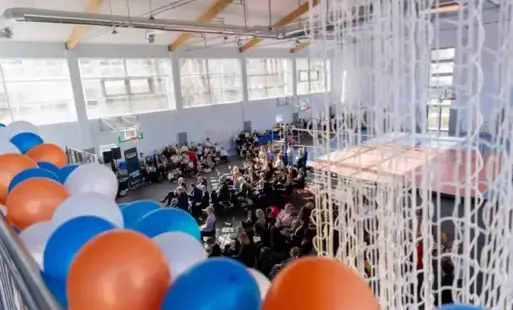 sala gimnastyczna z góry z goścmi siedzącymi na krzesełakach 