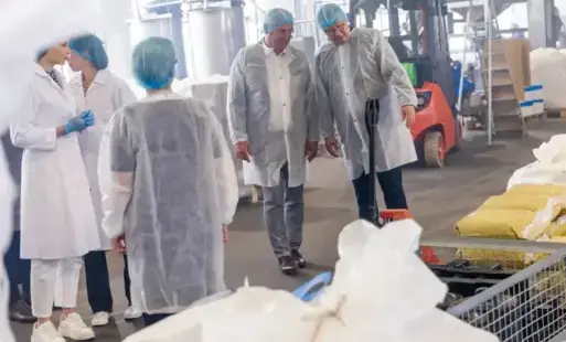 Ludzie w ochronnych ubraniach na hali produkcyjnej