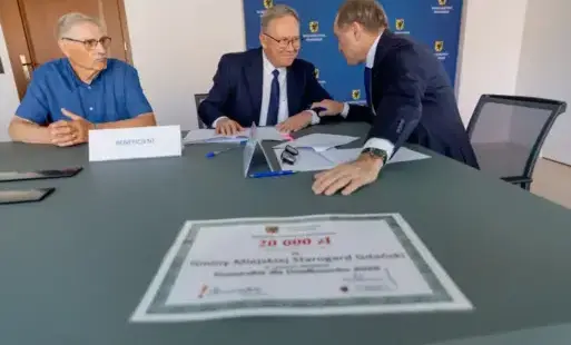 Trzch mężczyzn przy stole na którym leza dokumenty