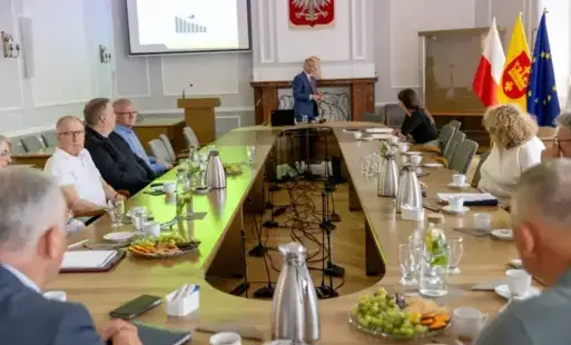 ludzie siedzą wokół owalnego stołu i dyskutują