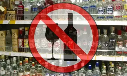półki z alkoholem w tle na pierwszym planie znak zakazu sprzedaży