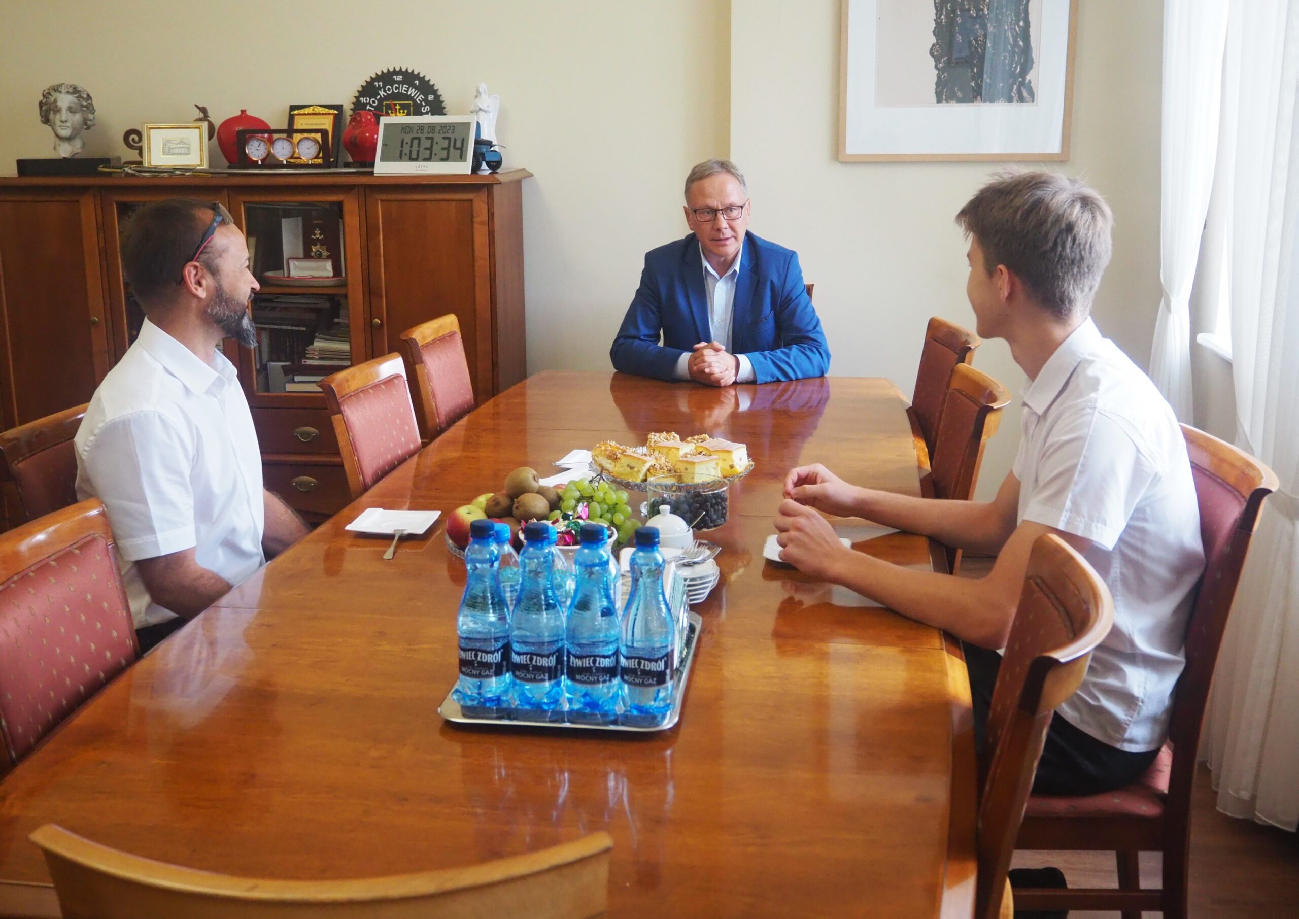 Krystian Krajnik i trener Tadeusz Kuzioła opowiedzieli Prezydentowi Miasta jak wyglądają przygotowania do zawodów. Trzy osoby siedzą przy stole. 
